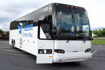 A white charter bus with the Falcon Charter Bus logo parked in Memphis